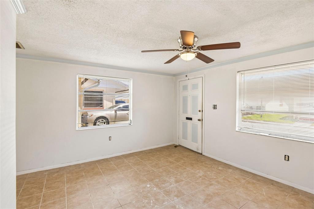 The exterior of a yellow, single-story building features a gabled roof and an air conditioner — 4923 GETNER STREET, NEW PORT RICHEY, FL