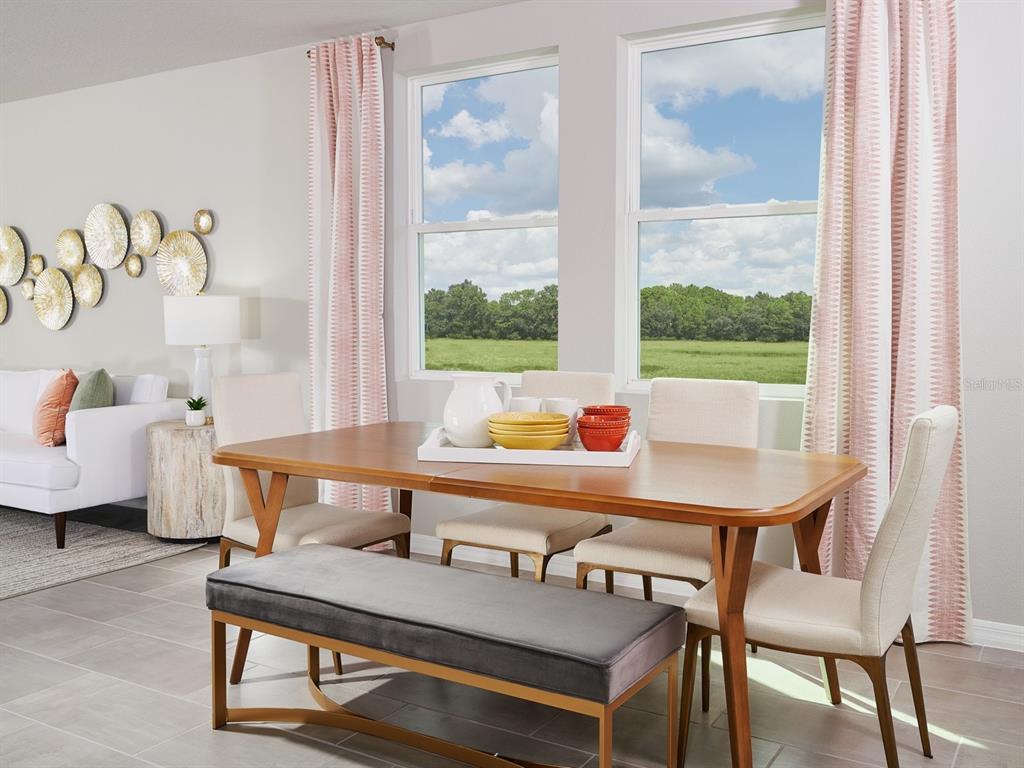 A dining room features a wooden table, chairs, a gray bench, and large windows — 3923 TEAK LANE, PARRISH, FL