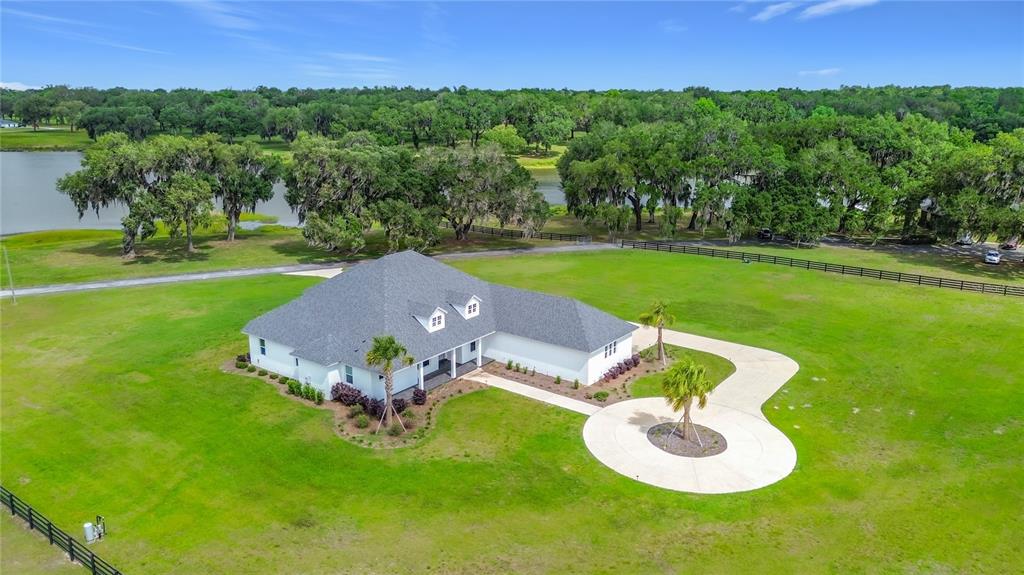 An aerial view shows a large house with a dark roof situated on a grassy estate — 6530 SE 156TH LOOP UNIT 3 & 4, SUMMERFIELD, FL