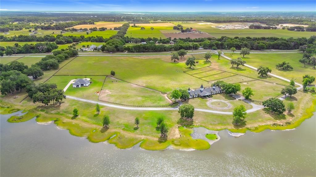 An aerial view of a white horse stable with three cupolas beside a lake — 6530 SE 156TH LOOP UNIT 3 & 4, SUMMERFIELD, FL