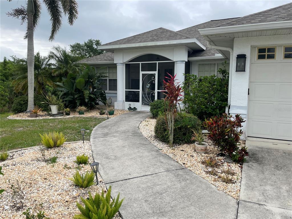 A concrete walkway leads to the screened front entryway of a single-story suburban home — 18029 OHARA DRIVE, PORT CHARLOTTE, FL