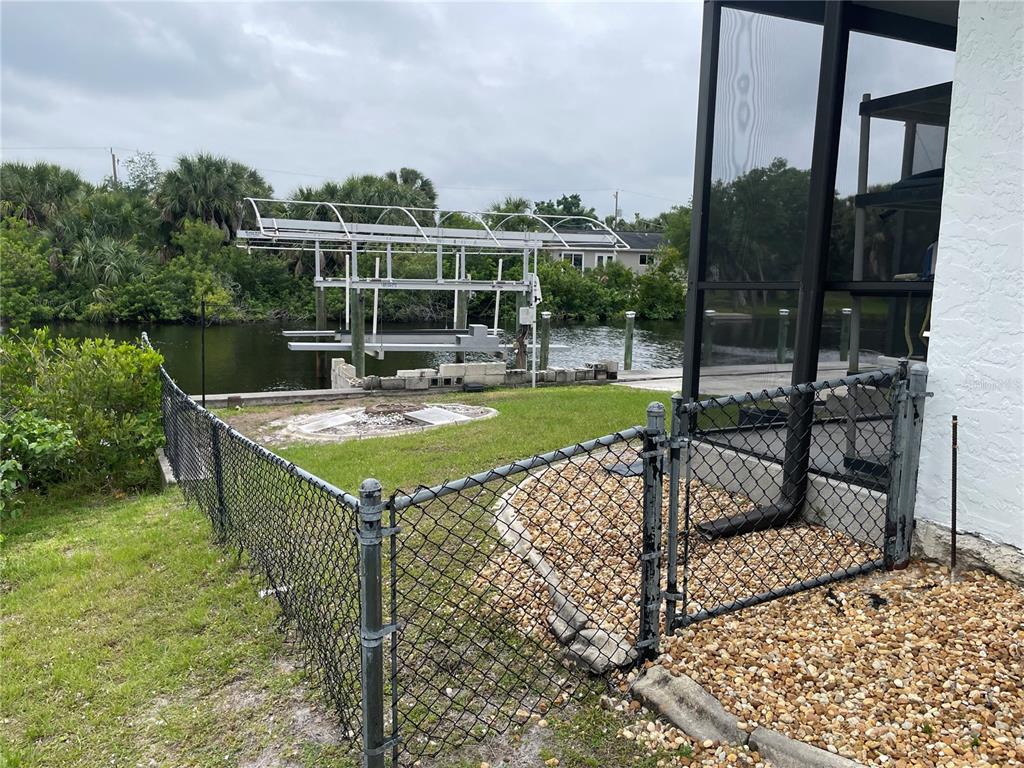 A backyard view features a boat lift, a chain-link fence, and a screened-in patio — 18029 OHARA DRIVE, PORT CHARLOTTE, FL