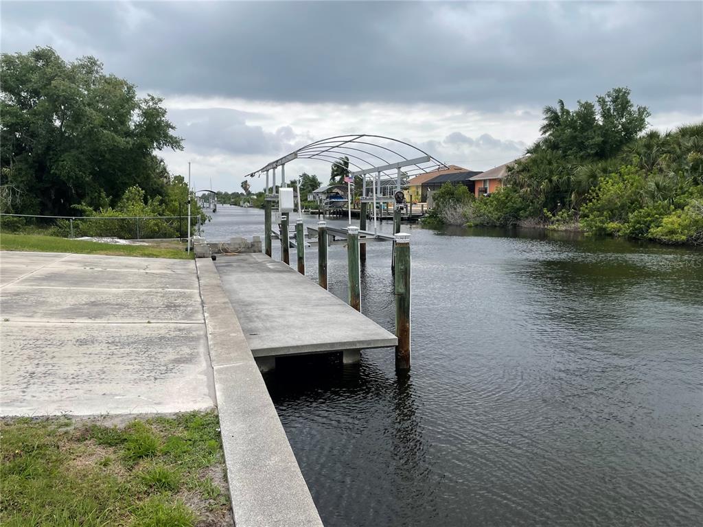 A concrete boat ramp and dock with a metal boat lift frame along a canal — 18029 OHARA DRIVE, PORT CHARLOTTE, FL