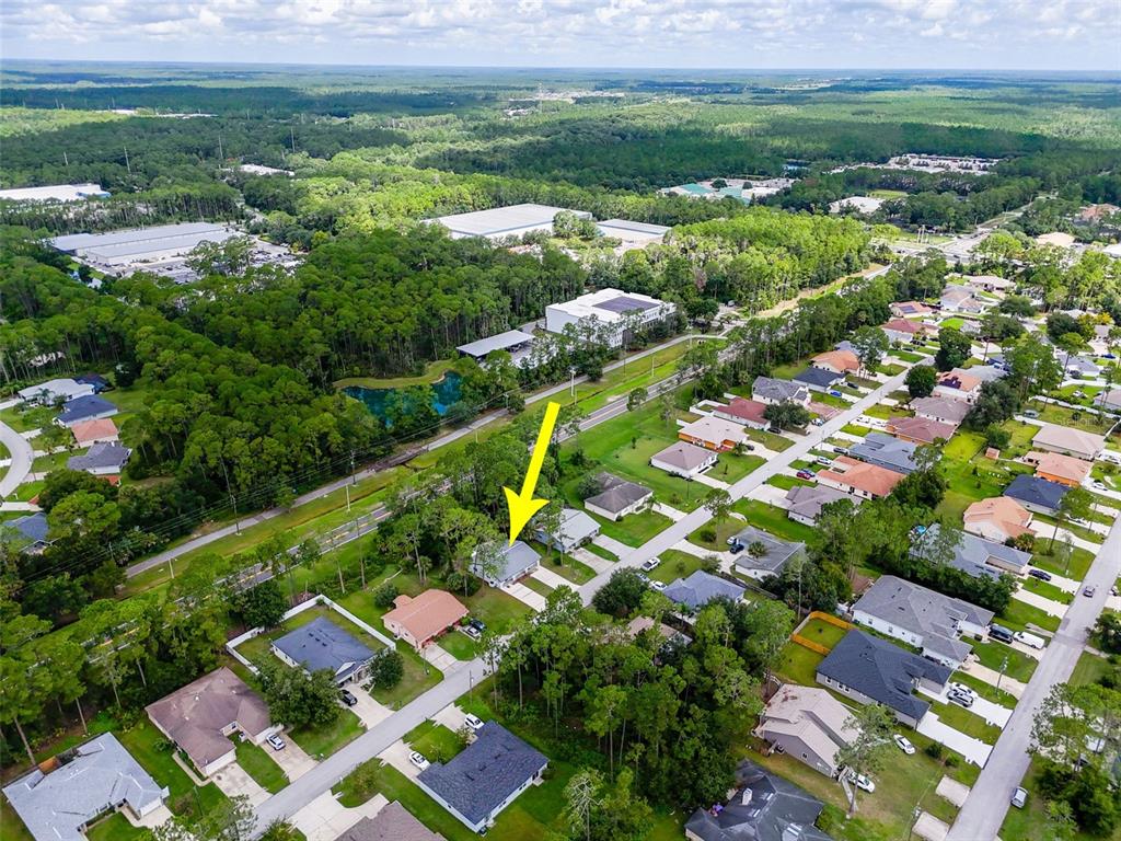 An aerial view shows a suburban neighborhood with a yellow arrow pointing to a house — 33 WELLWOOD LANE, PALM COAST, FL