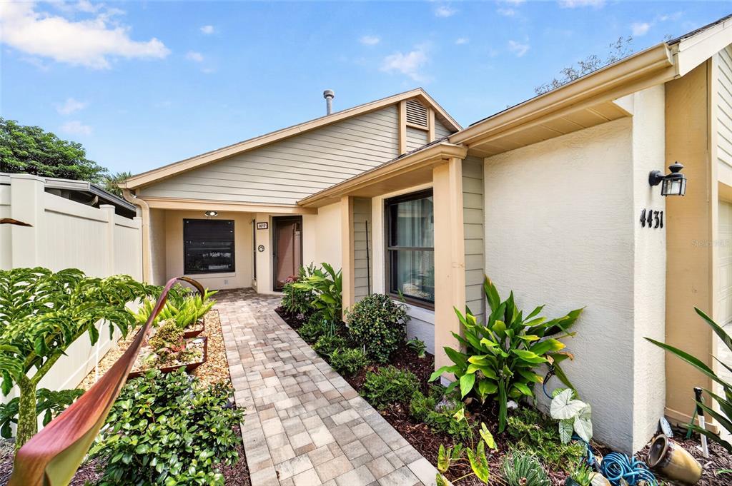 A paved walkway leads to the front entrance of a house with beige siding and stucco — 4431 NE 4TH STREET, OCALA, FL