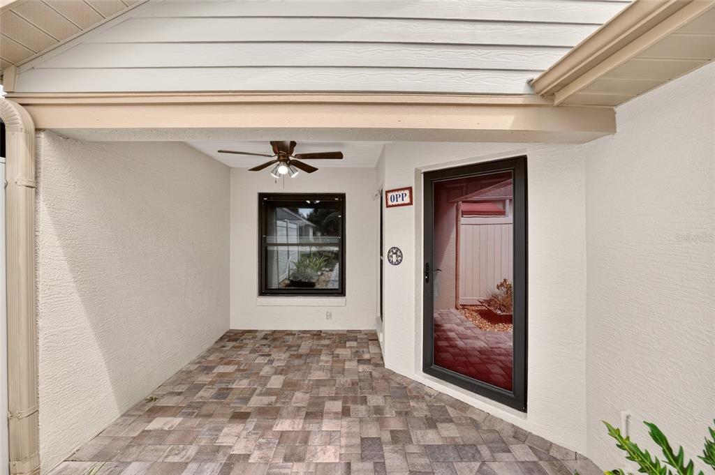 A covered patio with a tiled floor, a ceiling fan, and a glass-paneled entry door — 4431 NE 4TH STREET, OCALA, FL