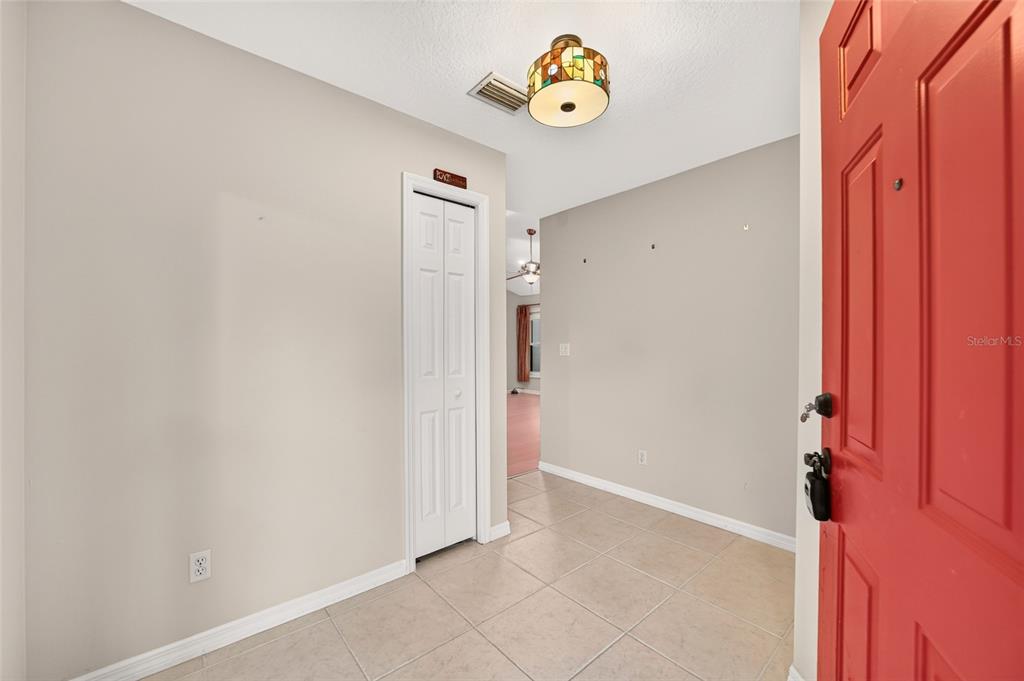 An entryway with beige tile floors, a red front door, and a stained-glass ceiling light — 4431 NE 4TH STREET, OCALA, FL