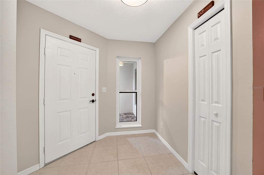A tiled entryway features a white front door, a narrow window, and a closet door — 4431 NE 4TH STREET, OCALA, FL