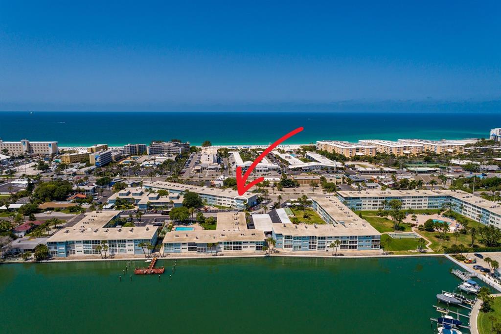 An aerial view shows a multi-story apartment building with a flat roof and parking lot — 6161 GULF WINDS DRIVE UNIT 338, ST PETE BEACH, FL