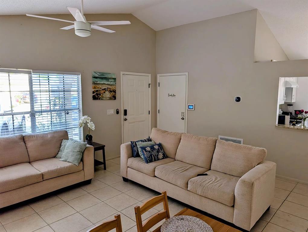 A living room with tile floors, two beige sofas, a ceiling fan, and vaulted ceilings — 1083 SNEAD AVENUE, SARASOTA, FL