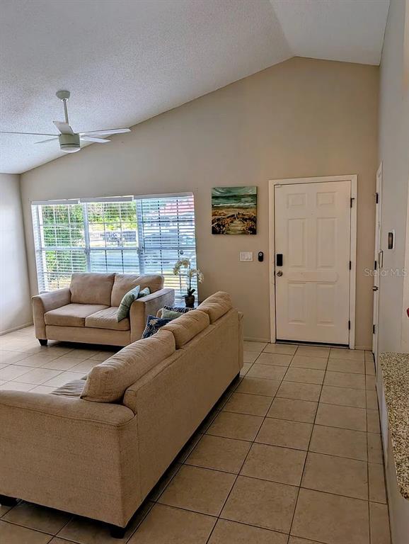 A living room features beige sofas, a vaulted ceiling with a fan, and tiled flooring — 1083 SNEAD AVENUE, SARASOTA, FL