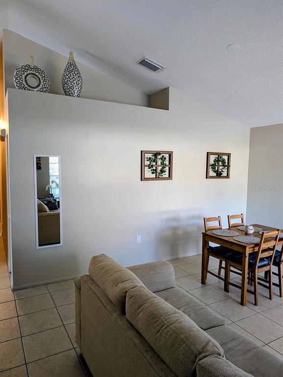 A living room features a beige sofa, a dining set, and wall decor under a vaulted ceiling — 1083 SNEAD AVENUE, SARASOTA, FL