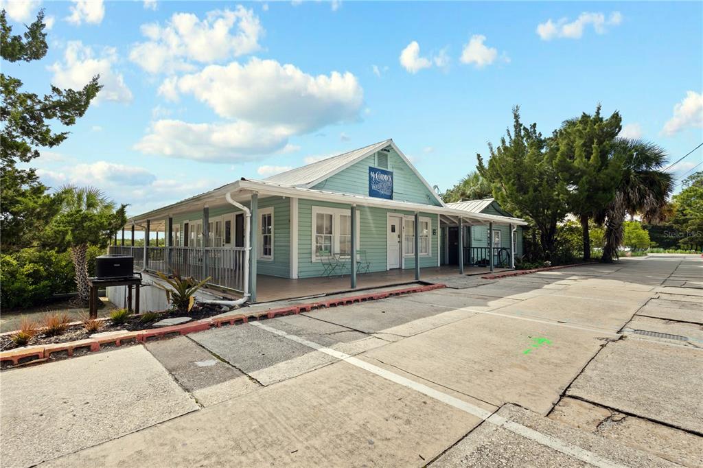 A light green, single-story commercial building with a wrap-around porch and a metal roof — 4051 D STREET, CEDAR KEY, FL