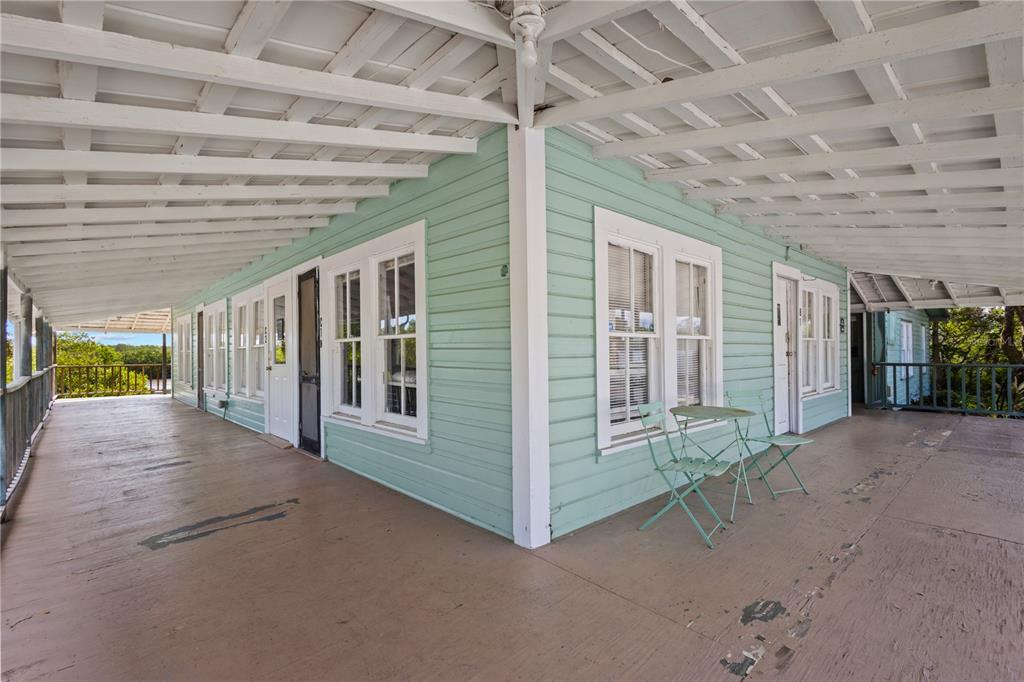 A wide, covered wrap-around porch with light green siding and white trim on a house — 4051 D STREET, CEDAR KEY, FL