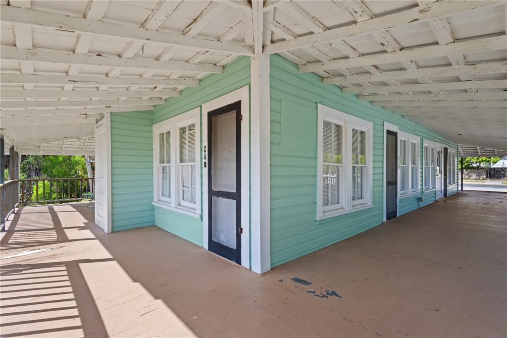 A wide, covered porch wraps around a light green building with white trim and windows — 4051 D STREET, CEDAR KEY, FL