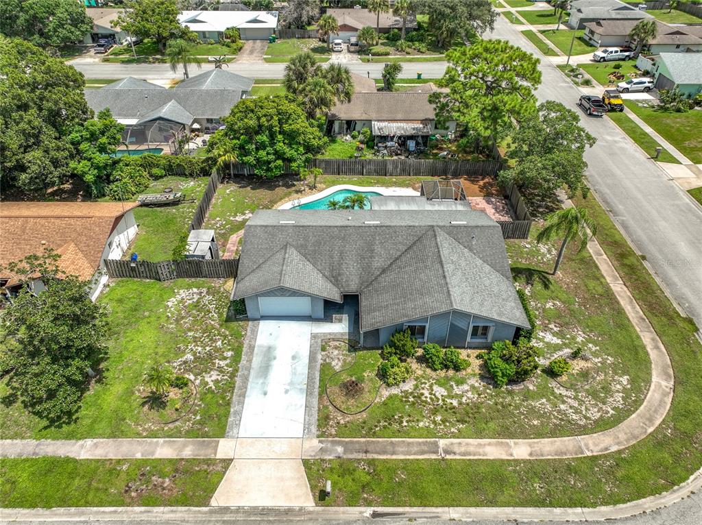 An aerial view shows a single-story house with a swimming pool and a concrete driveway — 2983 ONTARIO CIRCLE W, MELBOURNE, FL
