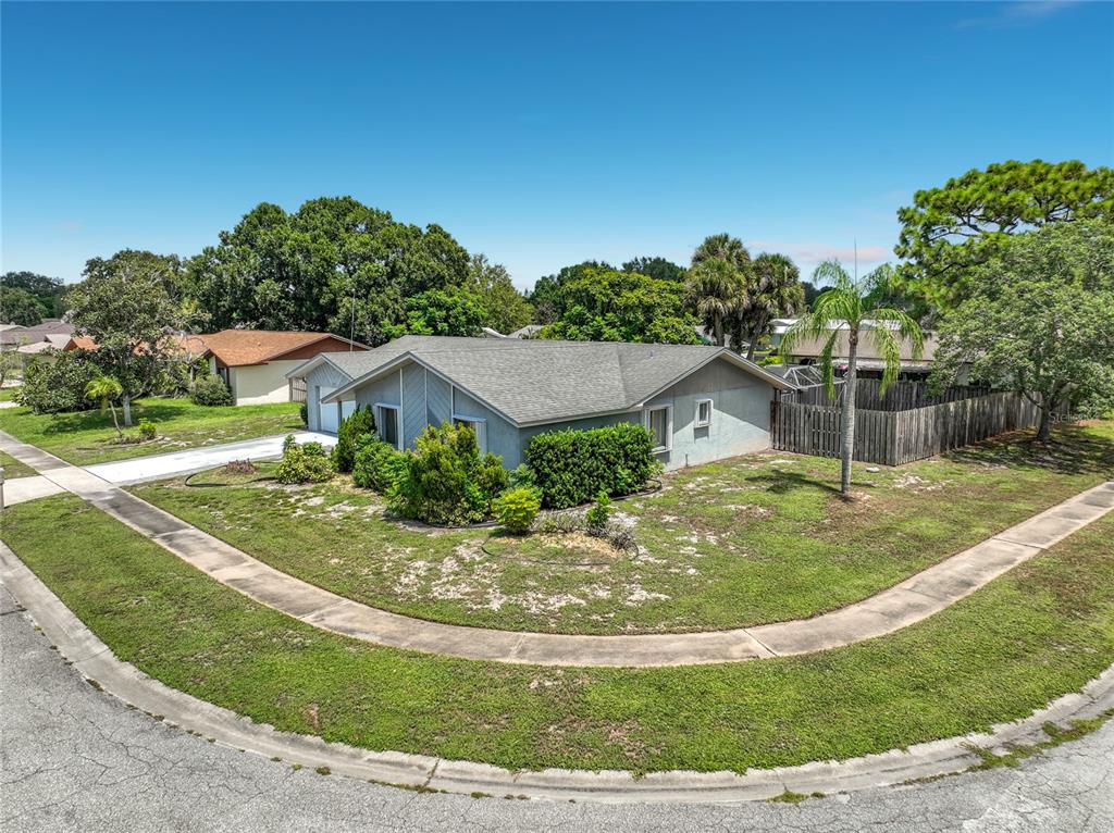 A single-story house with a gray exterior sits on a corner lot with landscaping — 2983 ONTARIO CIRCLE W, MELBOURNE, FL