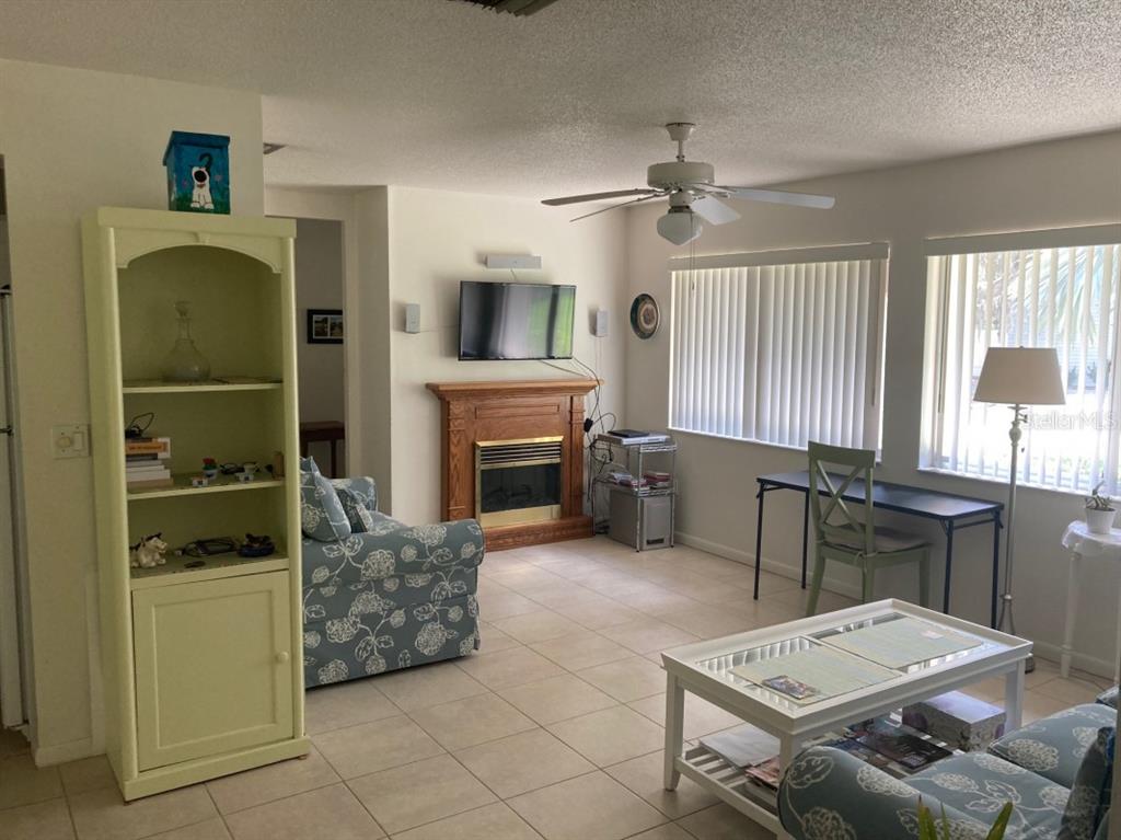 A living room features tile floors, a fireplace with a television, and a ceiling fan — 3415 ALLAPATCHEE DRIVE, PUNTA GORDA, FL