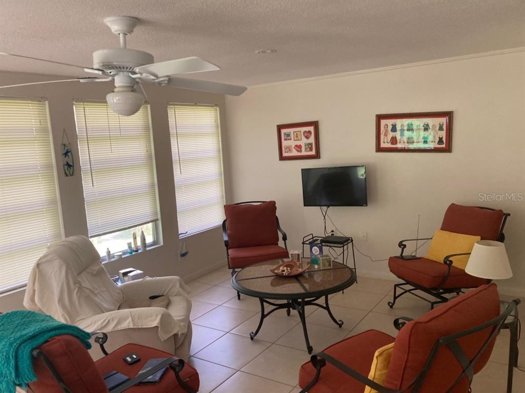 A living room features tile flooring, a ceiling fan, and several chairs around a table — 3415 ALLAPATCHEE DRIVE, PUNTA GORDA, FL