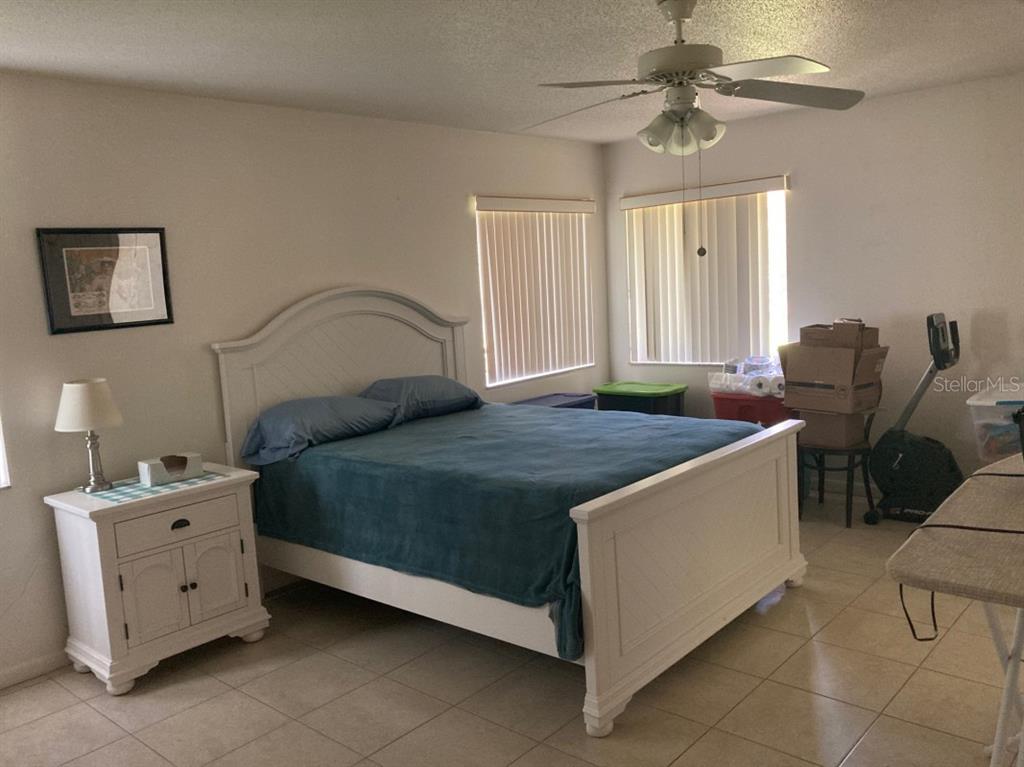 A bedroom features a white bed frame, a matching nightstand, and tile flooring — 3415 ALLAPATCHEE DRIVE, PUNTA GORDA, FL