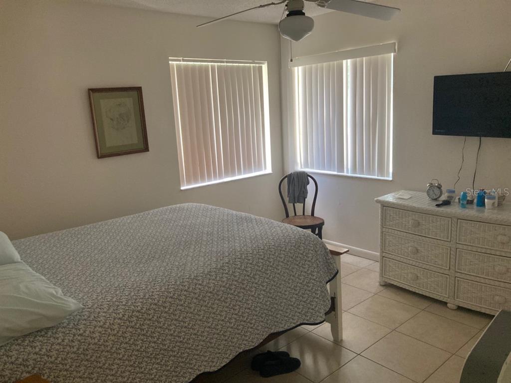 A bedroom features a bed, a wicker dresser, a wall-mounted television, and two windows — 3415 ALLAPATCHEE DRIVE, PUNTA GORDA, FL