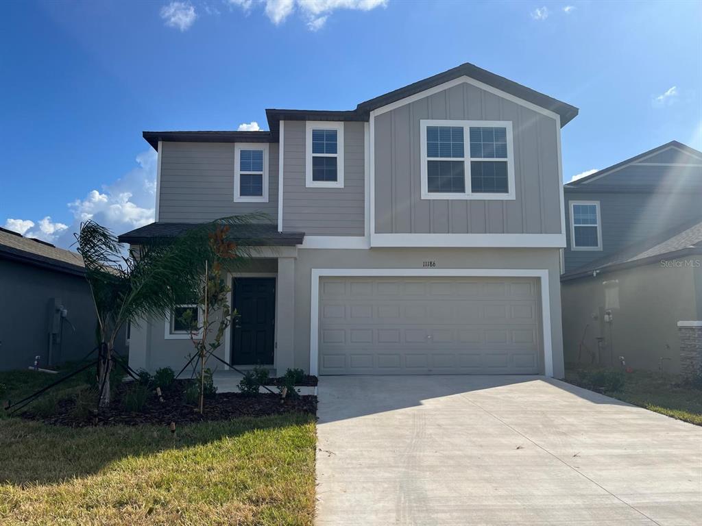 A two-story house with a beige stucco lower level, gray siding upper level, and garage — 11186 RADIANT SHORE LOOP, SAN ANTONIO, FL