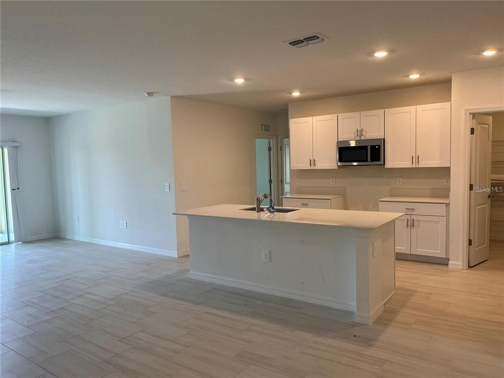 A kitchen with white cabinets, a central island, and light-colored tile flooring — 11186 RADIANT SHORE LOOP, SAN ANTONIO, FL