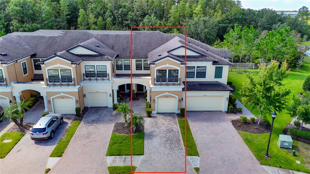 An aerial view shows a tan townhouse with a paved driveway and a two-car garage — 30305 SOUTHWELL LANE, WESLEY CHAPEL, FL