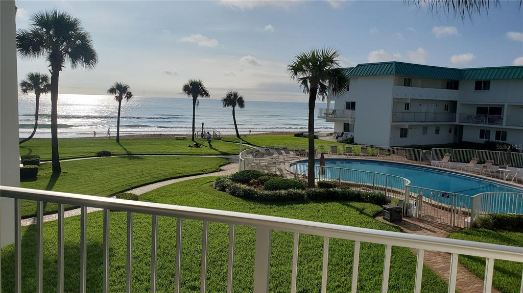 A view from a balcony overlooking a grassy lawn, swimming pool, and the ocean — 815 OCEAN SHORE BOULEVARD UNIT 9B, ORMOND BEACH, FL