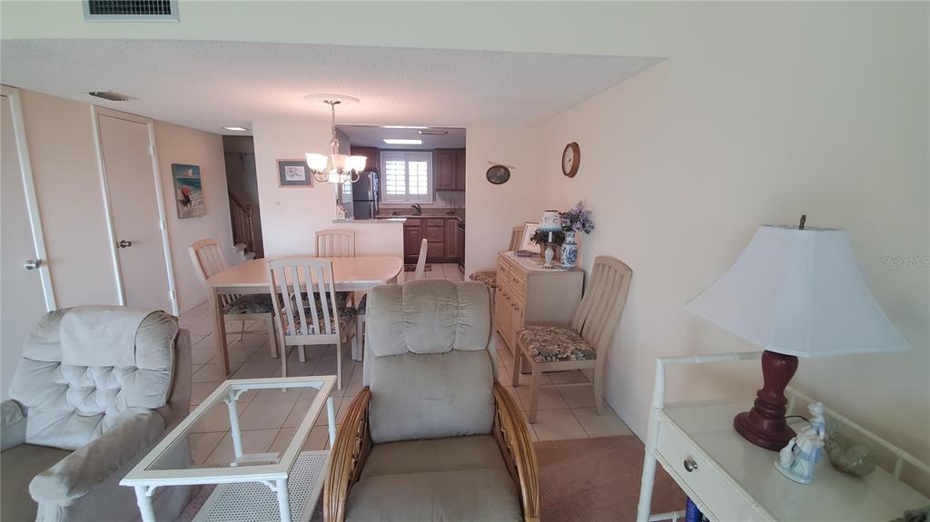 A dining area with a table and chairs sits adjacent to a kitchen and living space — 815 OCEAN SHORE BOULEVARD UNIT 9B, ORMOND BEACH, FL