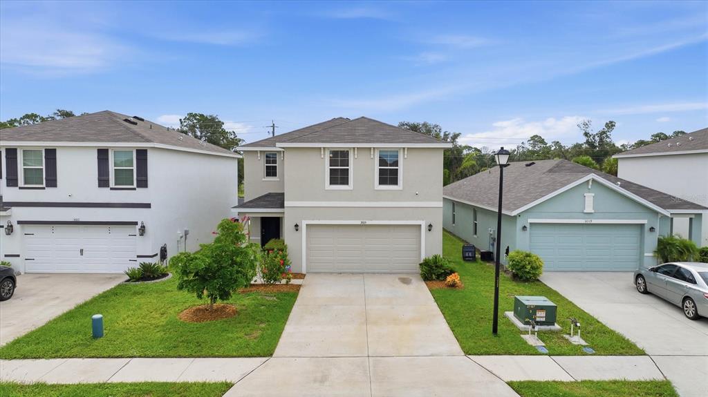 A two-story house with a beige stucco exterior sits between two neighboring homes — 3015 GREAT ABACO WAY, BRADENTON, FL