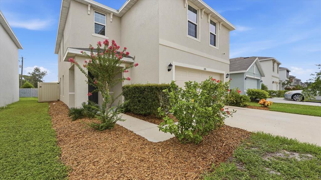 A two-story beige house with a garage, front landscaping, and a concrete driveway — 3015 GREAT ABACO WAY, BRADENTON, FL