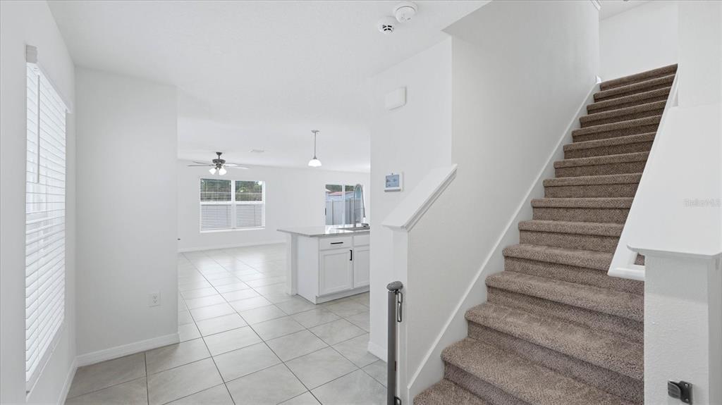 A view from a tiled entryway toward a kitchen with a staircase on the right — 3015 GREAT ABACO WAY, BRADENTON, FL