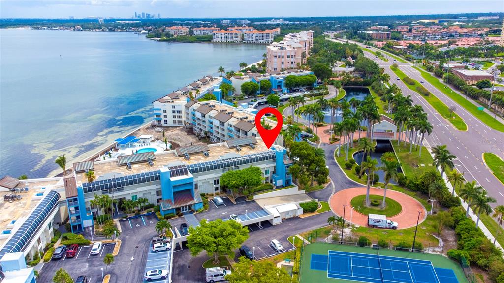 An aerial view shows a multi-story apartment complex with a pool, tennis court, and parking — 5277 ISLA KEY BOULEVARD S UNIT 124, ST PETERSBURG, FL