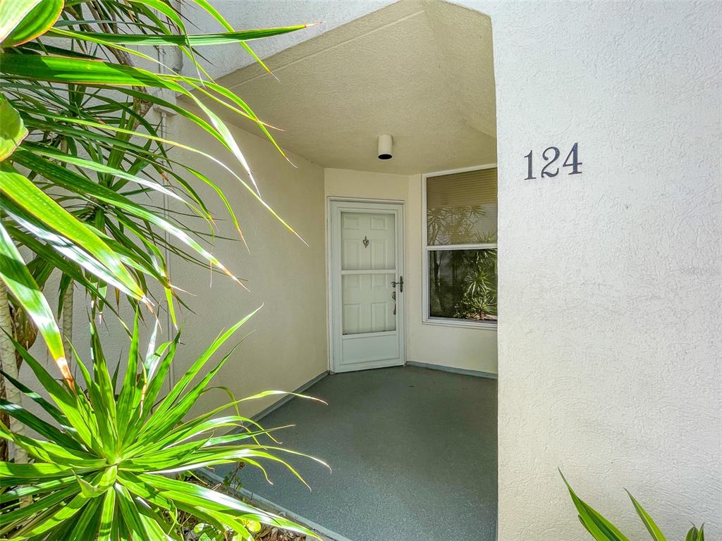 An exterior view of a residential entryway with a white door and the number 124 — 5277 ISLA KEY BOULEVARD S UNIT 124, ST PETERSBURG, FL