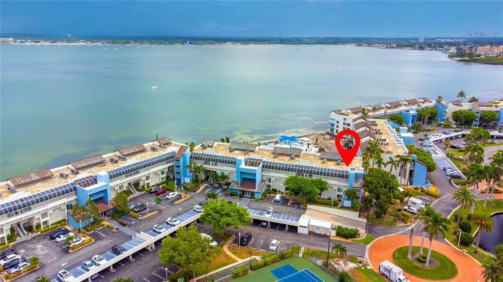 An aerial view shows a multi-story waterfront apartment complex with parking lots and a tennis court — 5277 ISLA KEY BOULEVARD S UNIT 124, ST PETERSBURG, FL