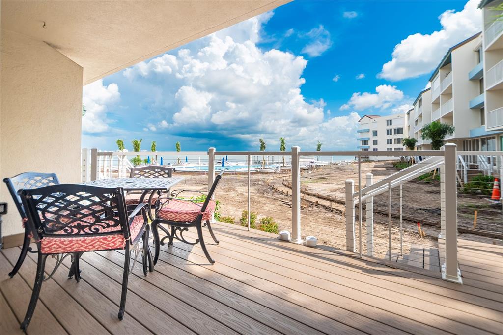 A balcony with patio furniture overlooks a construction site, a swimming pool, and the ocean — 5277 ISLA KEY BOULEVARD S UNIT 124, ST PETERSBURG, FL