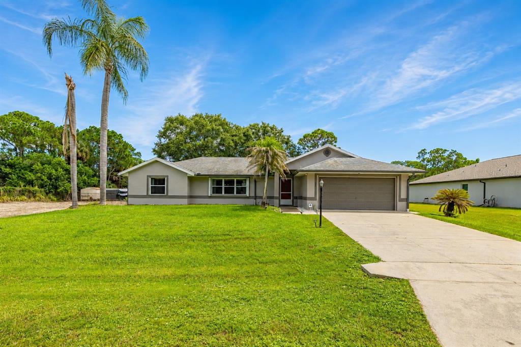 A single-story house with a gray exterior, a two-car garage, and palm trees in front — 1299 AMADOR AVENUE NW, PALM BAY, FL