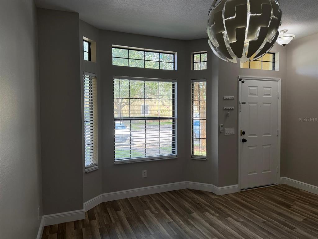 A dining room features a chandelier, a window with red curtains, and a pass-through opening — 6037 SCOTCHWOOD GLEN UNIT 8, ORLANDO, FL
