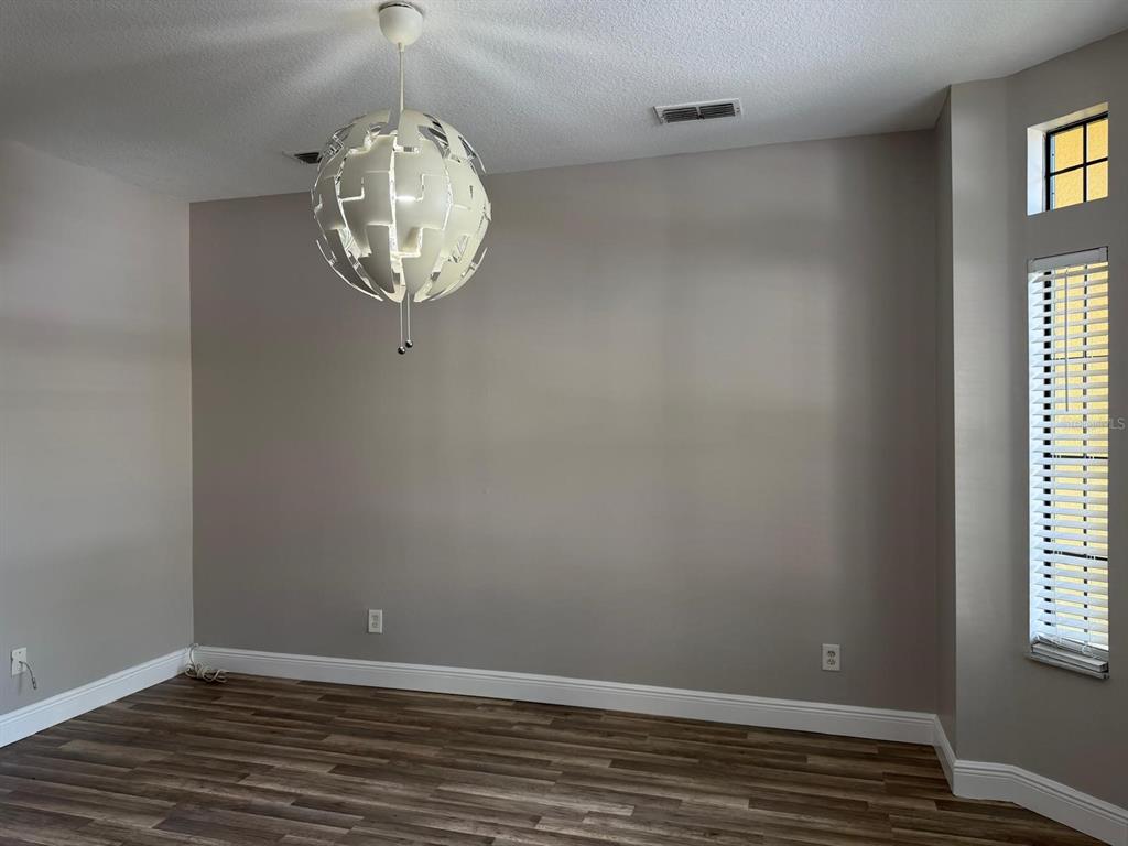 A carpeted living room features a ceiling fan and a staircase with decorative wall art — 6037 SCOTCHWOOD GLEN UNIT 8, ORLANDO, FL