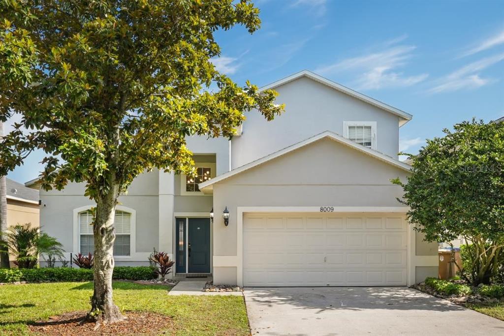 A two-story house with a light gray exterior, a two-car garage, and a front tree — 8009 ACADIA ESTATES COURT, KISSIMMEE, FL
