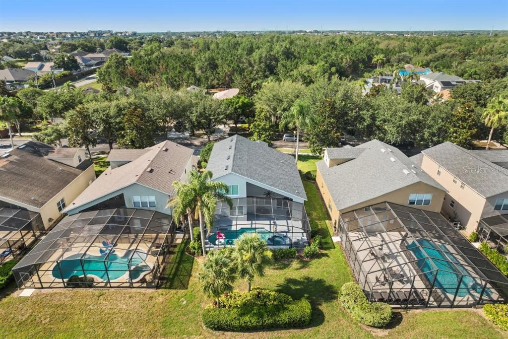 An aerial view of three suburban houses with screened-in swimming pools and backyard landscaping — 8009 ACADIA ESTATES COURT, KISSIMMEE, FL