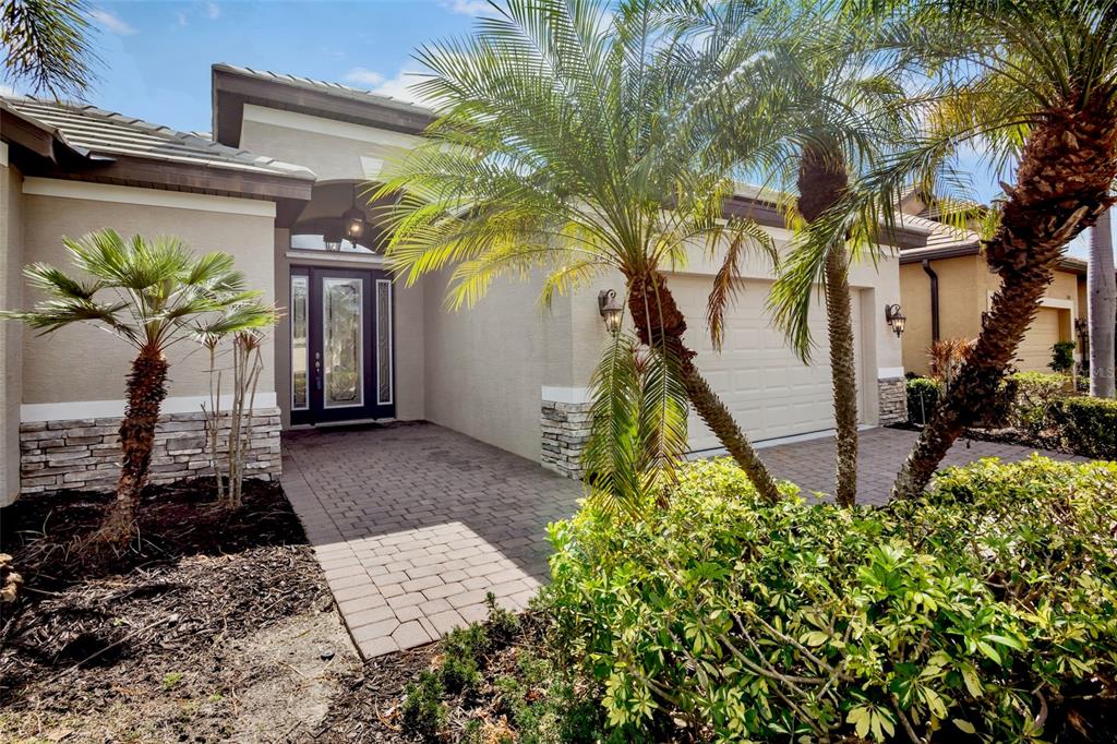 A single-story house with a beige exterior, a two-car garage, and palm trees in front — 7608 RIO BELLA, BRADENTON, FL