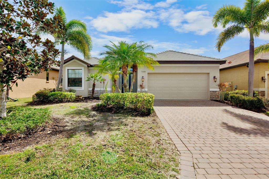 A single-story house with a palm tree, landscaping, and a white car in the driveway — 7608 RIO BELLA, BRADENTON, FL