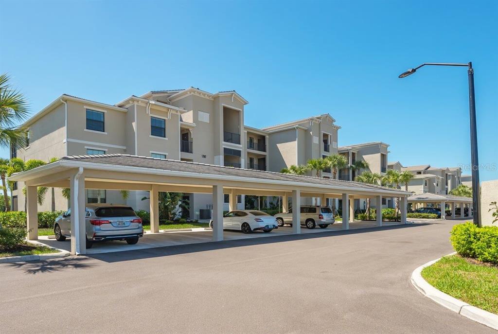 A multi-story apartment building with a covered parking structure in the foreground — 17902 GAWTHROP DRIVE UNIT 304, LAKEWOOD RANCH, FL