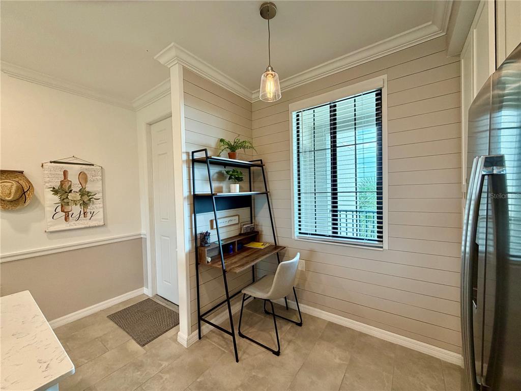 A kitchen nook features a desk, a chair, shiplap walls, and a window with blinds — 17902 GAWTHROP DRIVE UNIT 304, LAKEWOOD RANCH, FL