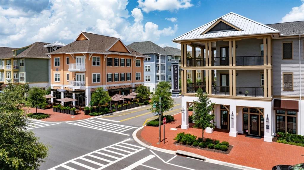 An exterior view shows multi-story buildings with balconies, storefronts, and a brick-paved street intersection — 1801 ISLAND VILLAGE WAY UNIT 307, CELEBRATION, FL