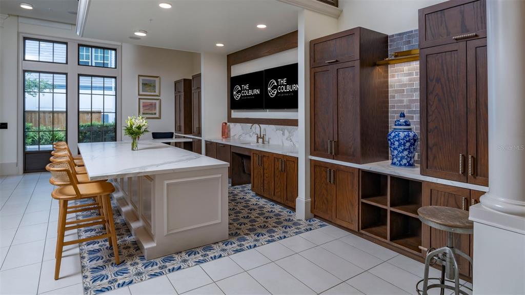 A kitchen area features a large white marble island, dark wood cabinetry, and patterned floor tiles — 1801 ISLAND VILLAGE WAY UNIT 307, CELEBRATION, FL