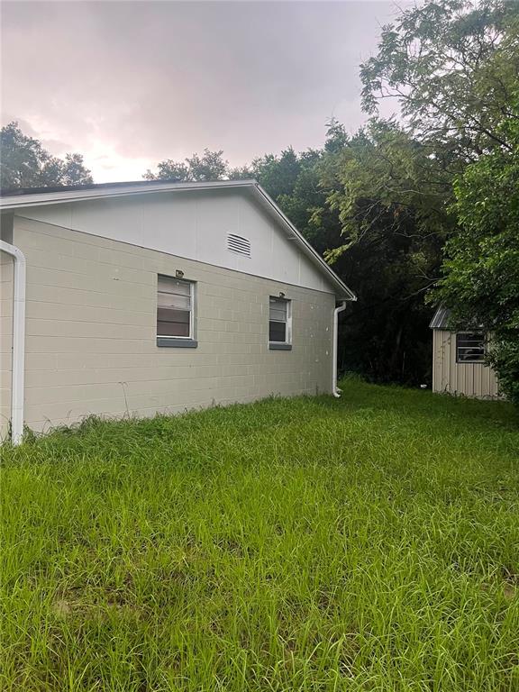 The exterior of a light-colored concrete block house with a small shed in the yard — 833 LONGVIEW AVENUE, DELAND, FL
