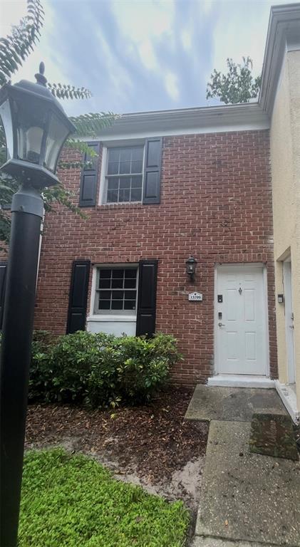A two-story brick townhouse exterior features black shutters, a white front door, and a lamppost — 13709 JUNIPER BLOSSOM DRIVE UNIT 0, TAMPA, FL